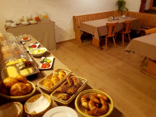 a table topped with baskets of bread and pastries at Schönblick Hotel Garni Ferienwohnungen in Lindenberg im Allgäu