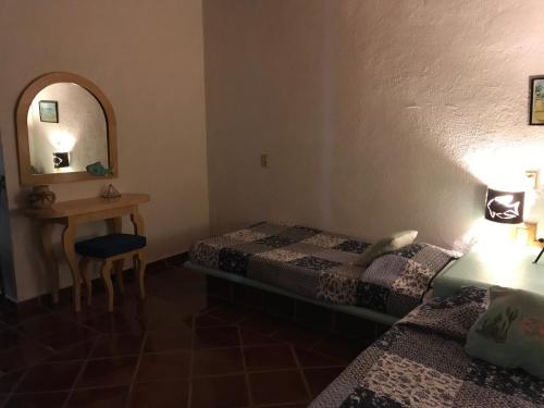 1 dormitorio con cama, mesa y espejo en Casa Constelaciones, en Tepoztlán