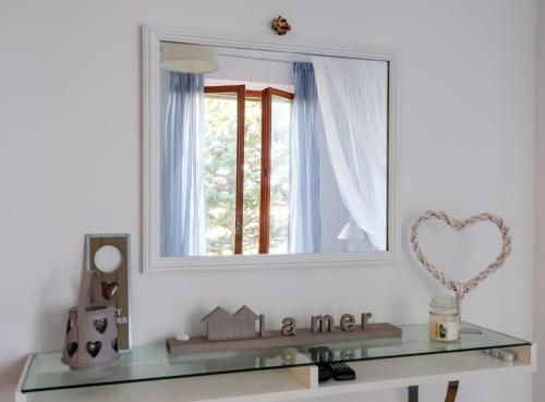 a mirror on a wall above a glass shelf with a window at ilmareinmezzo in Porto Recanati