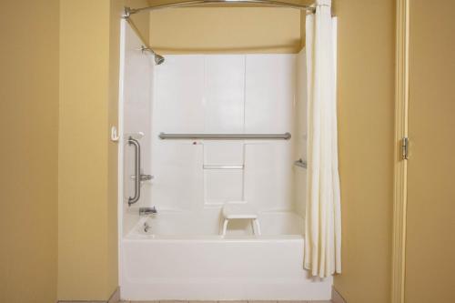 a bathroom with a shower with a white tub at Super 8 by Wyndham Big Cabin/Vinita Area in Vinita