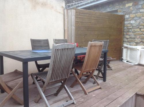 une table et des chaises noires sur une terrasse en bois dans l'établissement L'habitation de l'îlot entre mer et terre, à Wimille