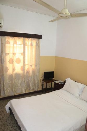 a bedroom with a white bed and a window at Hotel Aurore Lomé in Lomé