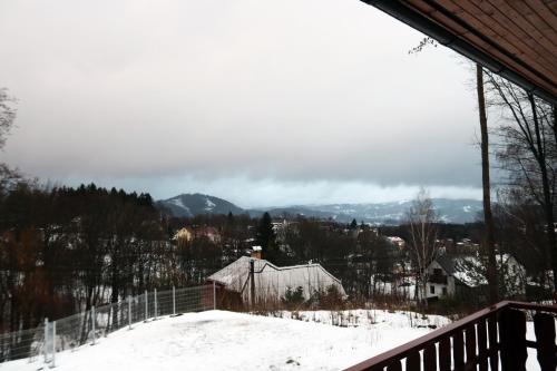a house in the snow with mountains in the background at Holiday Home Smržovka in Smržovka