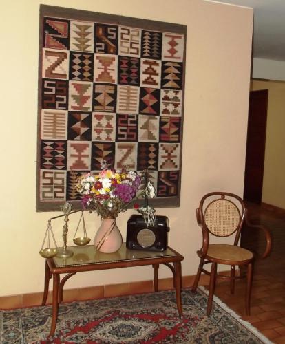 a table with a vase of flowers and a quilt on a wall at Hostal Gemina in Lima