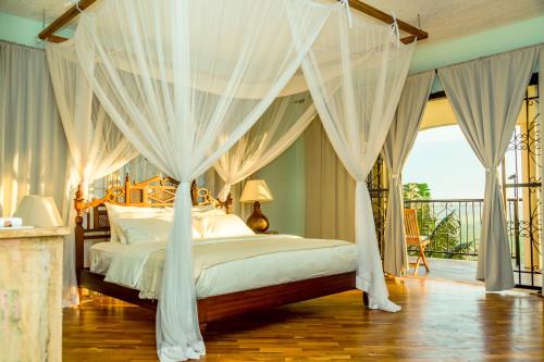 a bedroom with a canopy bed with white drapes at Ewange - A Casa Mia in Kampala