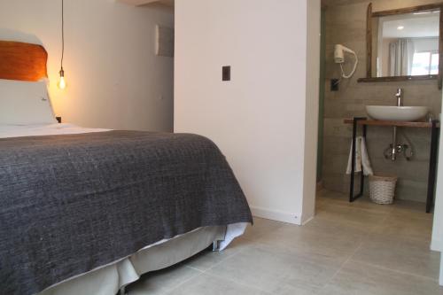 1 dormitorio con 1 cama y baño con lavamanos en Hotel Florinda en Punta del Este