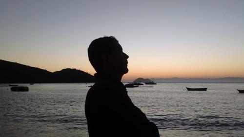 a man standing on the beach at sunset at Buzios Suites - com Garagem in Búzios