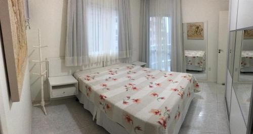 Dormitorio blanco con cama con colcha de flores en 3 dorms com vista a 250 mts do mar no centro da Meia Praia Itapema, en Itapema