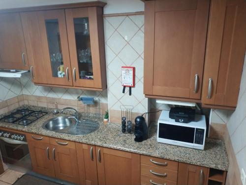 a small kitchen with a sink and a microwave at Alto Minho Central Apartment in Paredes de Coura