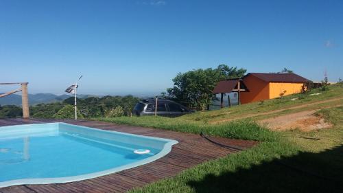 a blue swimming pool on a wooden deck with a house at Vista Magnata in Domingos Martins