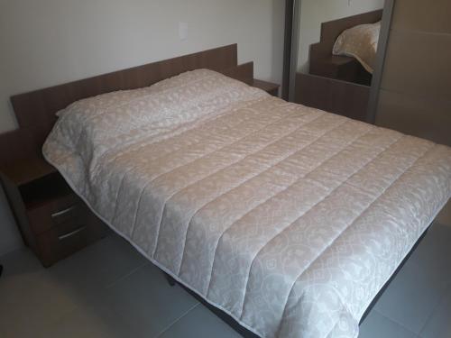 1 cama con edredón blanco en un dormitorio en Apt Interiro Praia de Itapema, en Itapema