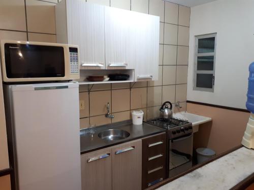 a small kitchen with a refrigerator and a sink at Lexus Residence 210 in Florianópolis