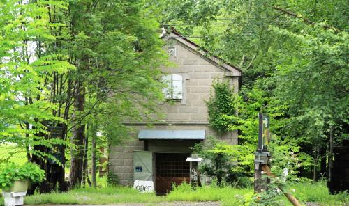 an old brick house with a garage in the woods at Gallery Stay Kitashajin in Higashikawa