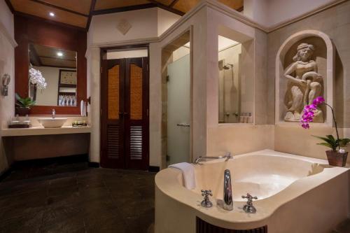 Bali Tropic Resort & Spa - CHSE Certified في نوسا دوا: حمام كبير مع حوض ومغسلة