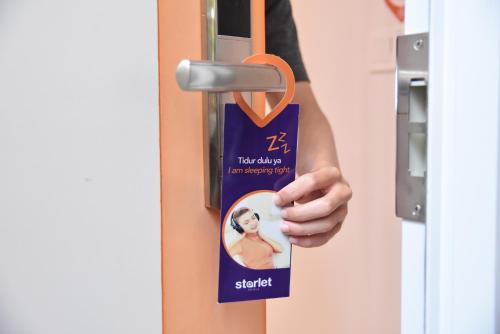 a person holding a key to a door at Starlet Hotel Serpong in Serpong