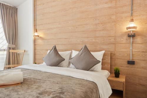 a bedroom with a large bed with a wooden wall at Vann House Hua Hin in Hua Hin