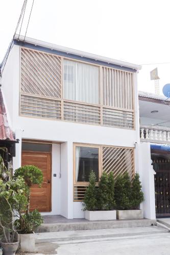 a white house with a wooden door and some plants at Vann House Hua Hin in Hua Hin