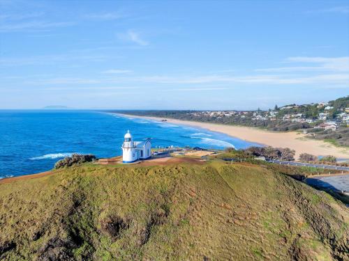 a lighthouse on top of a hill next to a beach at Surf Beach Motel Port in Port Macquarie