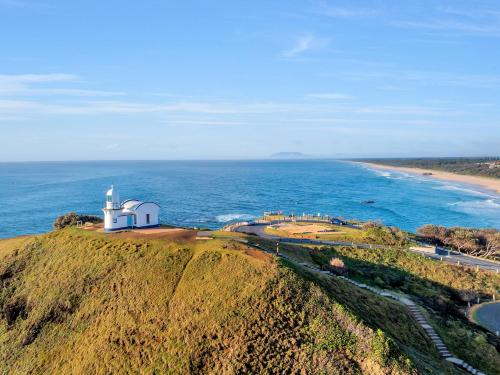 a lighthouse on top of a hill next to the ocean at Surf Beach Motel Port in Port Macquarie