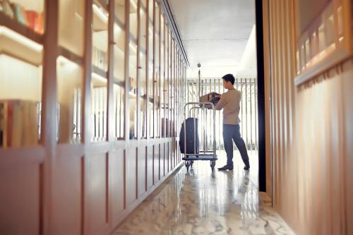 a man standing in a hallway with a luggage cart at Arcadia Suites Bangkok in Bangkok