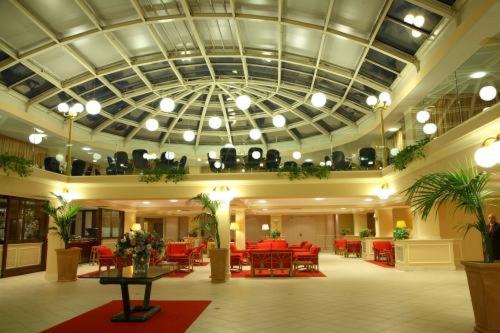 a lobby with red tables and chairs and a ceiling at Dioscuri Bay Palace in San Leone
