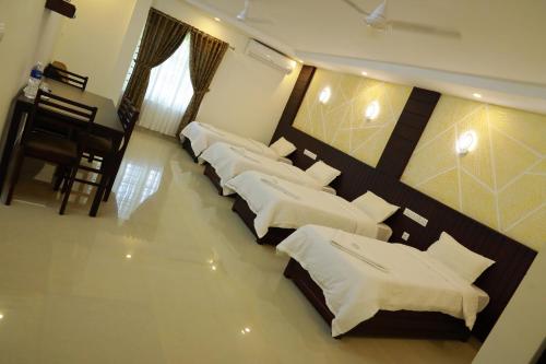a group of four beds in a room at Anna Residency in Nedumbassery