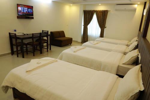 a hotel room with two beds and a dining room at Anna Residency in Nedumbassery