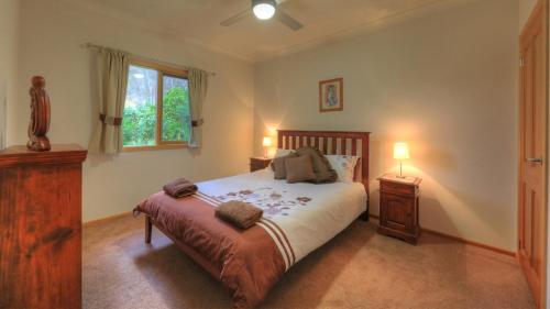 a bedroom with a bed and a night stand and a window at Alpine Riverside Accommodation in Myrtleford