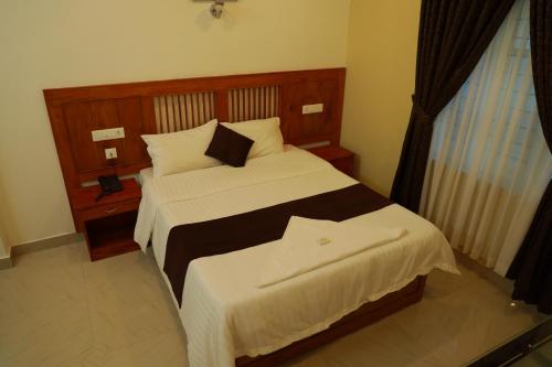 a bedroom with a large bed with white sheets at Anna Residency in Nedumbassery
