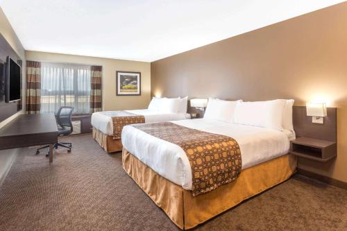A bed or beds in a room at Microtel Inn & Suites by Wyndham Whitecourt