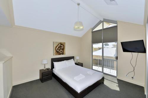 a bedroom with a bed and a flat screen tv at Serenity on the Terrace in Mandurah
