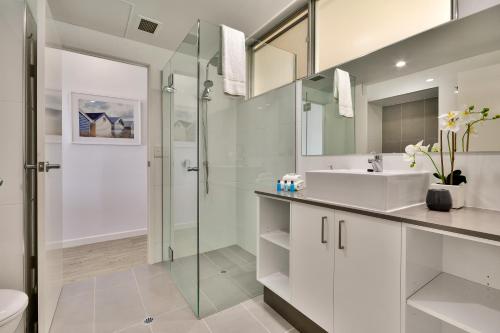 a white bathroom with a sink and a shower at Whitsunday Apartments on Hamilton Island by HIHA in Hamilton Island