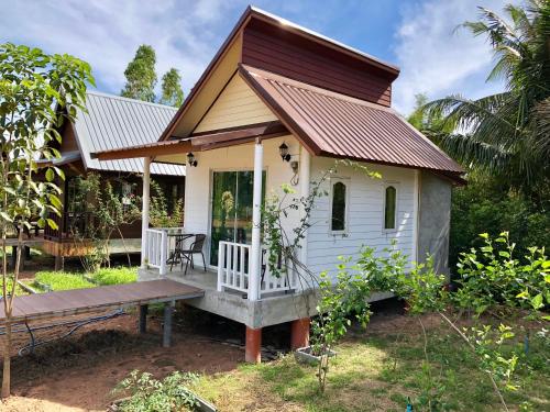 a small white house with a porch and a bench at Baan Thung Home Stay in Prasat