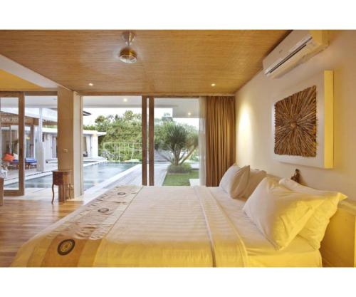 uma cama grande num quarto com uma janela grande em Sunset Paradise Villa Uluwatu em Uluwatu