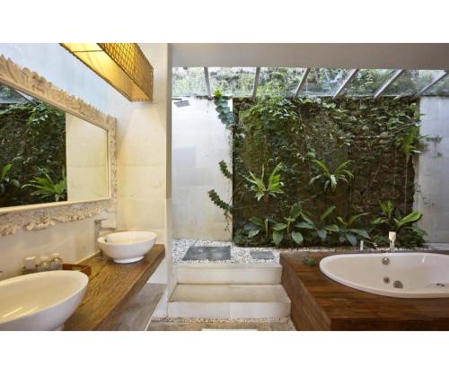 uma casa de banho com 2 lavatórios e uma banheira e uma planta em Sunset Paradise Villa Uluwatu em Uluwatu