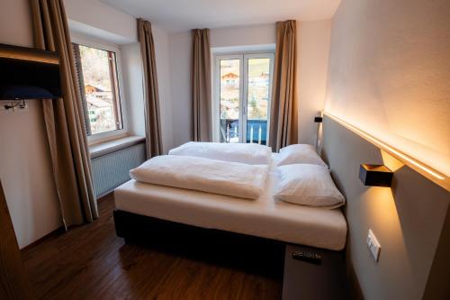a room with a bed with white pillows on it at Rider Hotel Obereggen in Obereggen