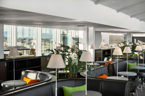 a waiting room with chairs and tables and windows at Wakeup Copenhagen - Bernstorffsgade in Copenhagen