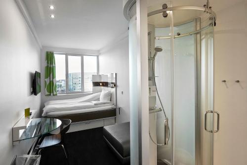 ein Bad mit Dusche und ein Bett in einem Zimmer in der Unterkunft Wakeup Copenhagen - Bernstorffsgade in Kopenhagen