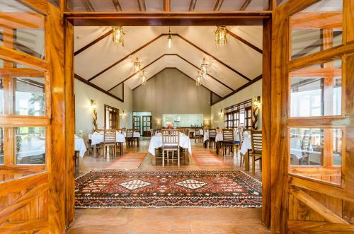 an open dining room with tables and chairs at Emburara Farm Lodge in Mbarara