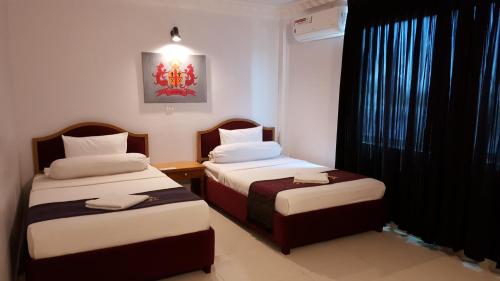 Kampong Chhnang帕玛酒店的有两张床和一扇窗户的酒店房间