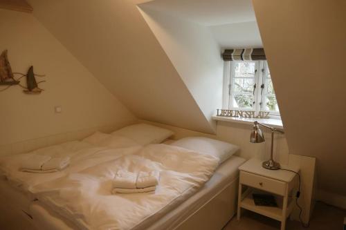 ein weißes Bett in einem Zimmer mit Fenster in der Unterkunft Lieblingsplatz in Wrixum