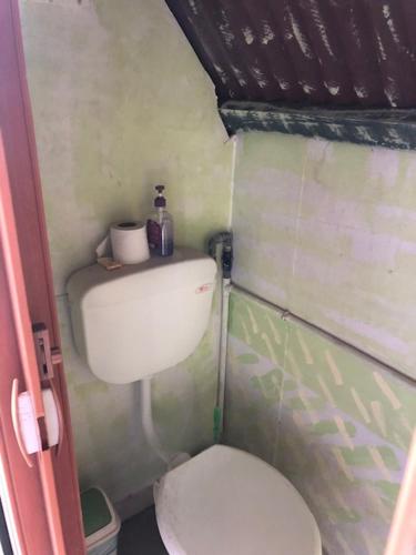 uma pequena casa de banho com um WC branco num quarto em Beach Shack Chalet - Garden View Aframe Small Unit em Ilha Tioman