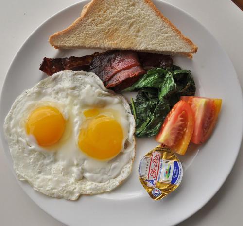 a plate of breakfast food with eggs bacon and toast at Ocean Terrace Suite And Spa Luxury in Nusa Penida