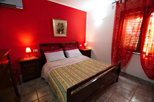 a bedroom with a red wall with a bed and two lamps at Il Fenicottero in Masainas