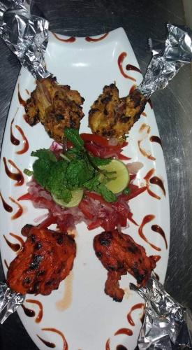 a plate of food with meat and vegetables on a table at Urban Rose Hotel & Apartments in Dar es Salaam