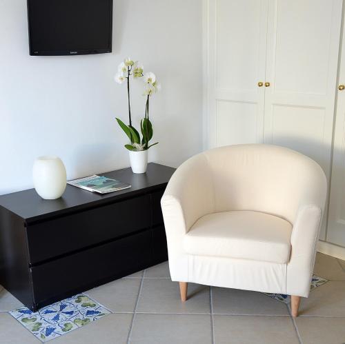 a living room with a white chair and a black dresser at B&B Il Vicolo in Anacapri
