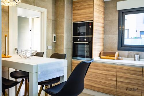 una cucina con tavolo bianco e sedie nere di BS Luxury Estate El Campello a El Campello