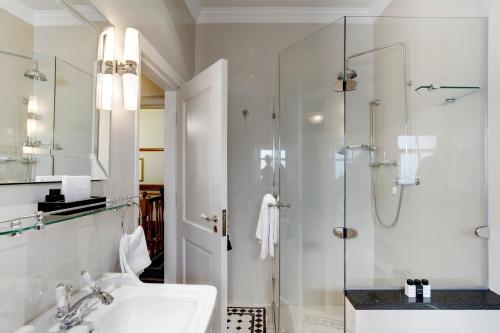 a white bathroom with a sink and a shower at Coopmanhuijs Boutique Hotel & Spa in Stellenbosch