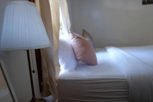 a bed with a pillow and a lamp next to a window at Paiyannoi Guesthome in Chiang Mai