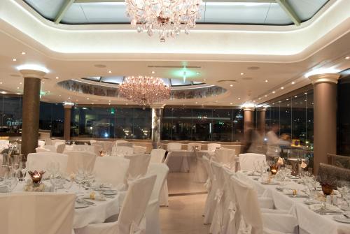 a banquet hall with white tables and chairs and a chandelier at The Athenian Callirhoe Exclusive Hotel in Athens
